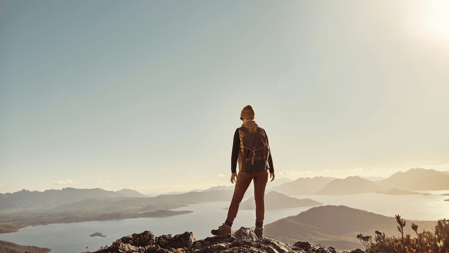 femme au sommet d'une montagne qui a dû sortir de sa zone de confort pour y arriver.